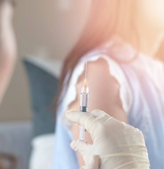 World immunization week and International HPV awareness day concept. Woman having vaccination for influenza or flu shot or HPV prevention with syringe by nurse or medical officer.