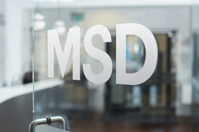 Logo MSD em adesivo em uma porta de vidro Em segundo plano temos um reflexo de um edifício